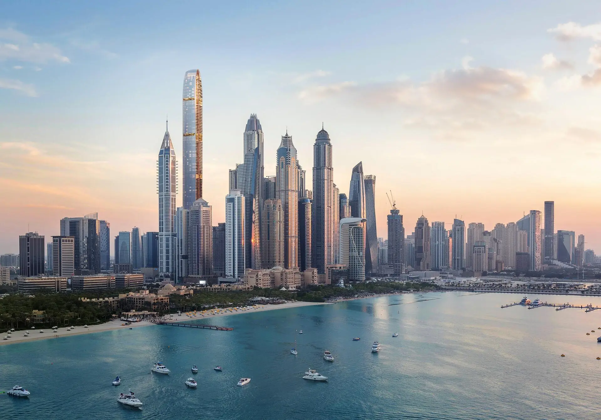 Dubai Marina skyline at sunset with luxury yachts and the Six Senses Residences by the waterfront.