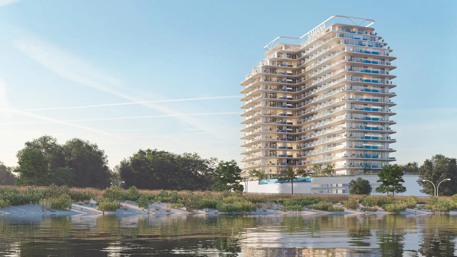 Modern waterfront tower "Samana Lake Views" with glass balconies, lush trees, and calm waters.