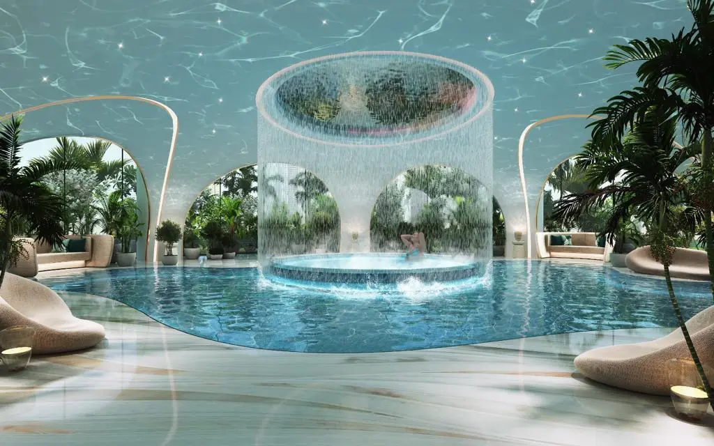 Luxury indoor pool with waterfall feature and lounge seating at Damac Casa Tower wellness area.