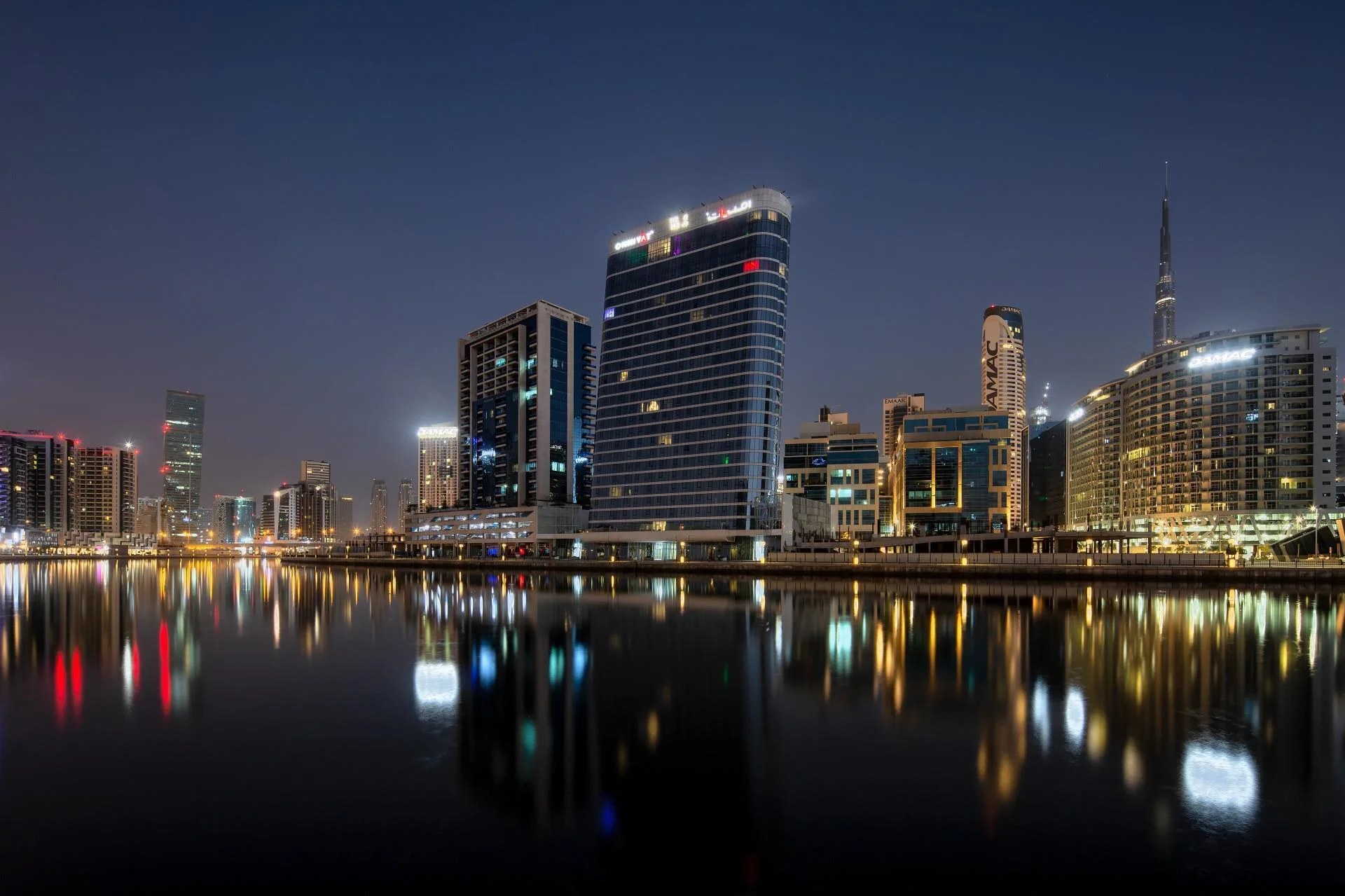 The Pad tower in Business Bay Dubai reflecting on canal at night with city skyline